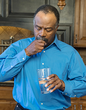 Man taking pills in kitchen.