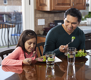 Man and girl eating healthy food at home.