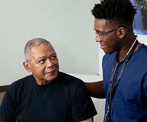 Health care provider talking to person in exam room.