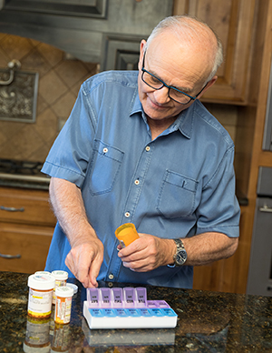 Man filling pill organizer with medicines..