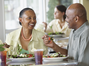 Man and woman sitting in restaurant eating salads.