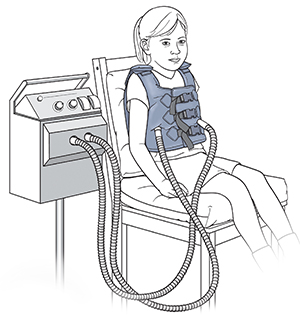 Child sitting in chair wearing vibrating vest.