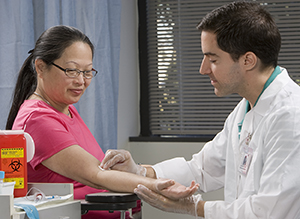 Healthcare provider preparing to take blood from woman’s arm.