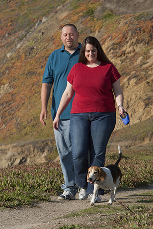 Man and woman outside, walking dog.