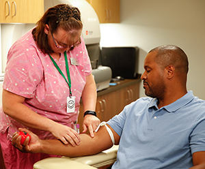 Healthcare provider drawing blood from man's arm.